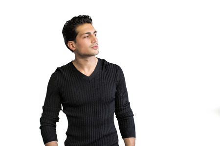 Brown eyed, black haired latin man standing on white background looking to a side