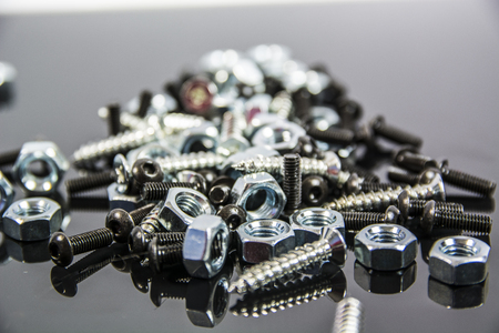 Close-up of heap of bolts, screws and nuts on neutral background in studio shotの写真素材