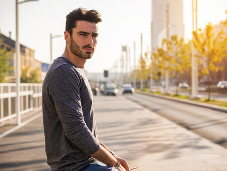 Attractive young bearded man portrait in urban environment, in a street, looking at cameraの写真素材