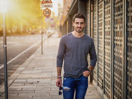 Attractive young bearded man portrait in urban environment, in a street, looking at camera smilingの写真素材