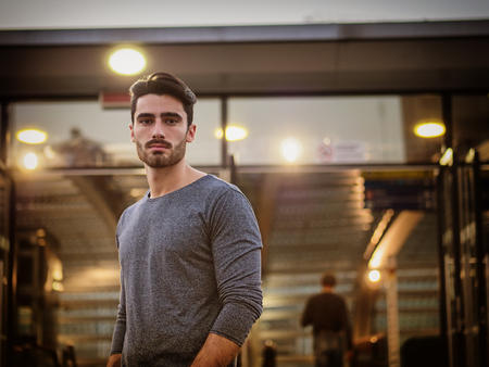 Handsome young man profile shot, indoor, inside big modern building, maybe a brand new train station, looking at cameraの写真素材