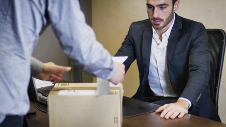 Businessman sitting in his office and looking at parcel delivered him by unrecognizable courier.の写真素材