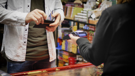 Man standing in shop and paying with his contactless credit card.の写真素材