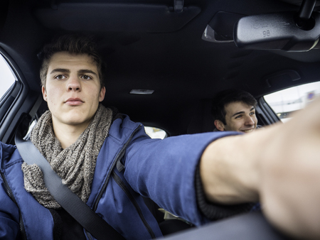 Young friends in warm clothing sitting in car and exploring dashboard while spending time together.