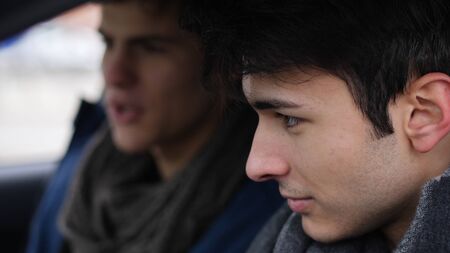 Young friends in warm clothing sitting in car and exploring dashboard while spending time together.の写真素材