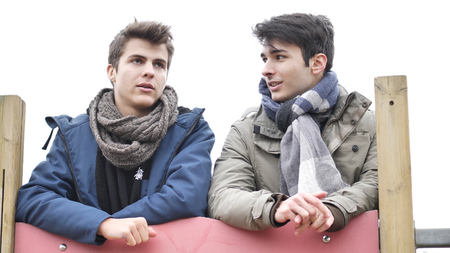From below view of young men in winter clothing talking while chilling outdoors.の写真素材