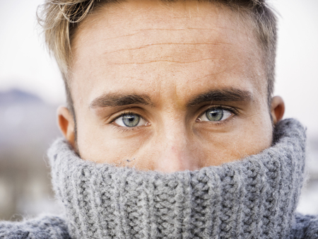 Headshot of handsome young man outdoor in winter fashion, wearing turtleneck sweater in snow environmentの写真素材