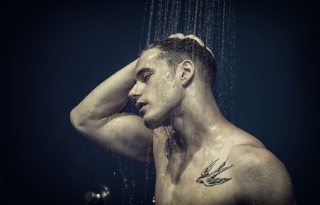 Close up Attractive Young Bare Muscular Young Man Taking Shower, with Eyes Closedの写真素材