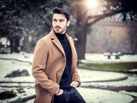 Handsome young man standing outside in winter, in snowy Turin, in Italy, in urban settingの写真素材