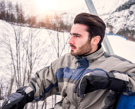 Man taking ride on chairlift while skiingの写真素材