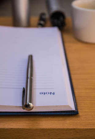 Pen resting on a notebook at a desk.の写真素材