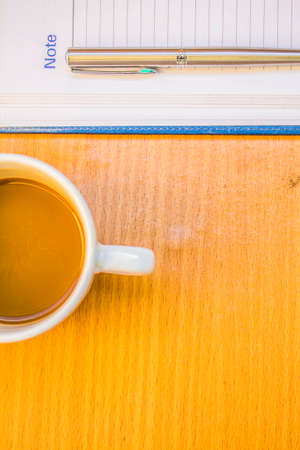 Pen on notebook and coffee at the table.の写真素材