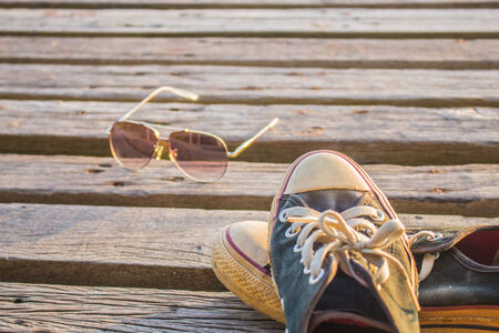 Sneakers are removed and placed on a wooden floor.の写真素材