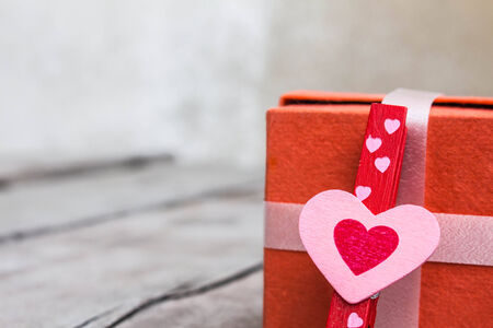 The heart symbol and orange gift box on a woodenの写真素材