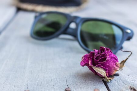 Dried roses and sunglasses on a woodenの写真素材