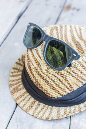 Glasses on a hat in the wooden table.の写真素材