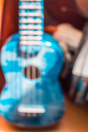 Blue ukulele on background blur.