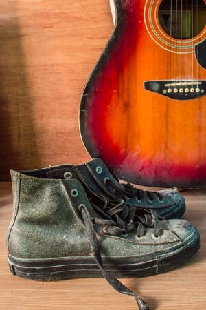 Old shoes and a guitar in a vintage wooden floor.の写真素材