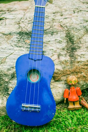 Ukulele and dolls on the background of rock.