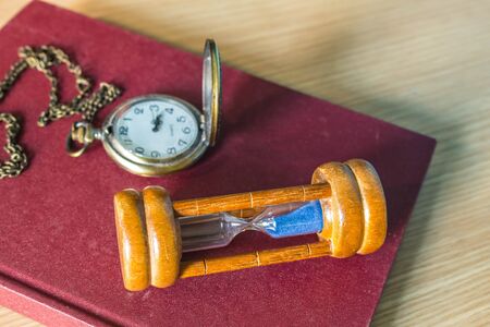 Hourglass and old books on a wooden