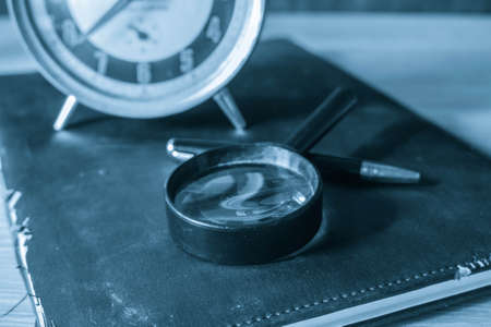Magnifying glass and old book on a woodenの写真素材