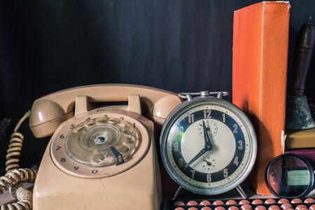 Old clock and telephone on the desk in the room.の写真素材