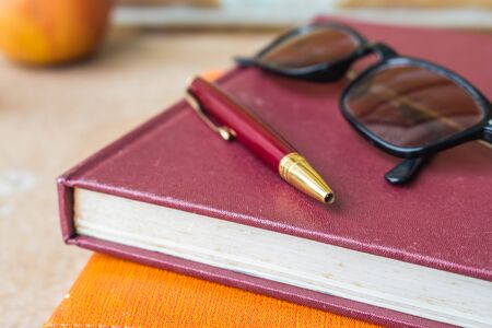 Pen and glasses placed on old books.の写真素材