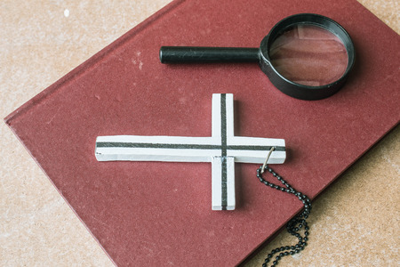 Cross and magnifying glass on old books.の写真素材