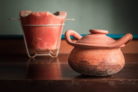 Old clay pot and stove on a wooden table.の写真素材