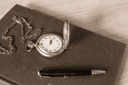 Pen and clock on the old dusty books.の写真素材