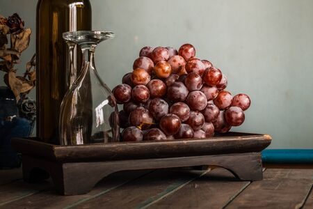 Grapes and a glass on old wooden tray.の写真素材