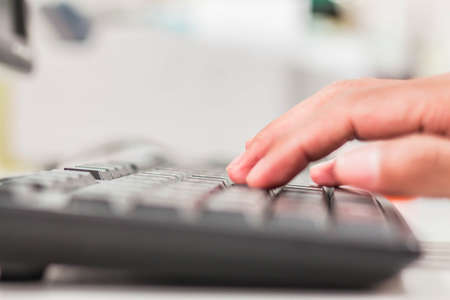 Blurred hands typing on a computer keyboard.