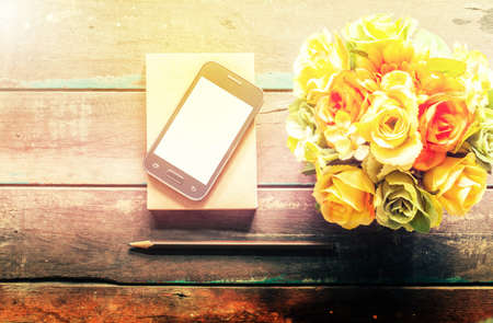 Mobile and vase of flowers on the old wooden floor.の写真素材