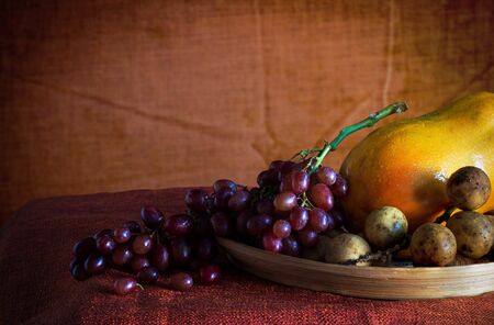 grapes and papaya on a wooden tray with of art.