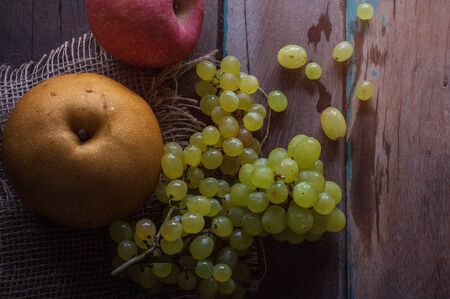 Grapes and pear on old wooden floor.の写真素材
