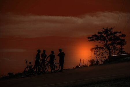 The cyclists stopped to rest on a mountain at sunset.の写真素材