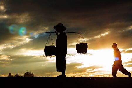 Farmer and son with silhouettes at sunset.の写真素材