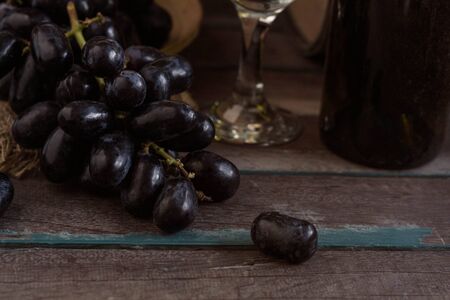 Black grapes and wine on a wooden table old.の写真素材