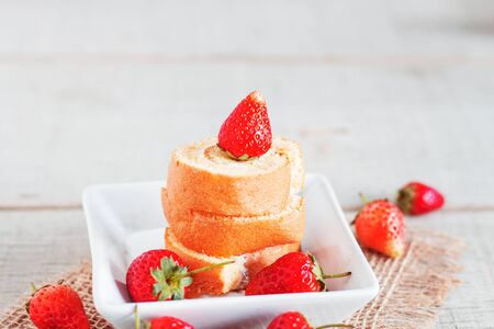 Roll cake and strawberries on the table.の写真素材