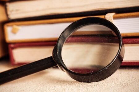 Old magnifying glass of dusty and books on desk.の写真素材