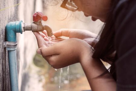 Girls are drinking water from the tap water in the park.の写真素材