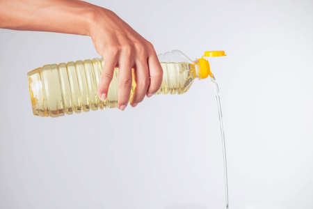 Hand is pouring vegetable oil on a white background.の写真素材