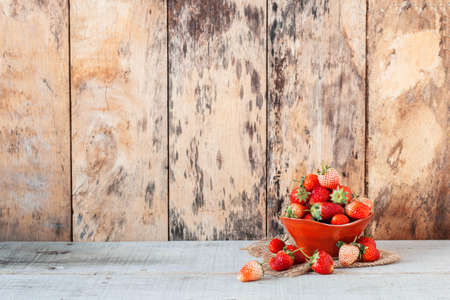 fresh strawberries in red cup on the wooden floor.の写真素材