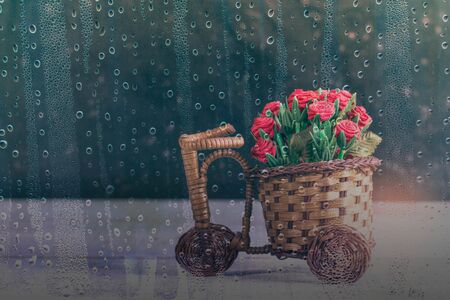 basket of roses looking through glass at the rain.の写真素材