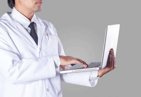 Male doctor is using a notebook with a gray background.の写真素材