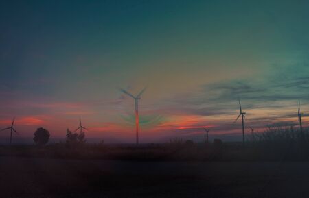 Wind farm with silhouettes at sunset.の写真素材