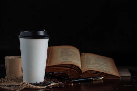 Cup of coffee and books on the table with black background.