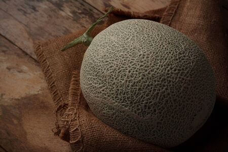 Melon and sackcloth on old wooden floor.の写真素材