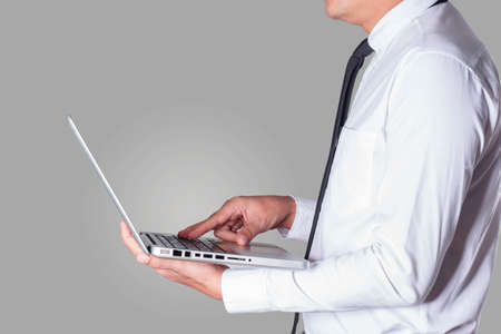 business man holding a laptop working on a gray background.の写真素材