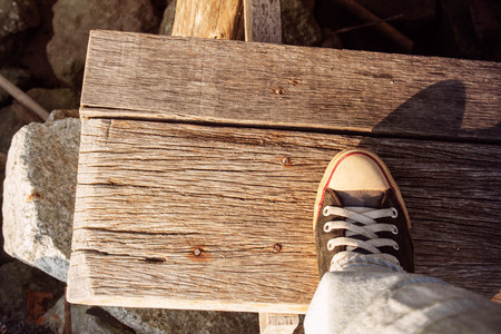 Foot sneakers stand on wooden stairs.